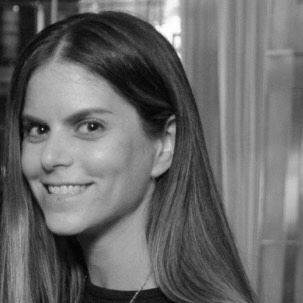 A woman with long hair smiles at the camera in a black-and-white photo.