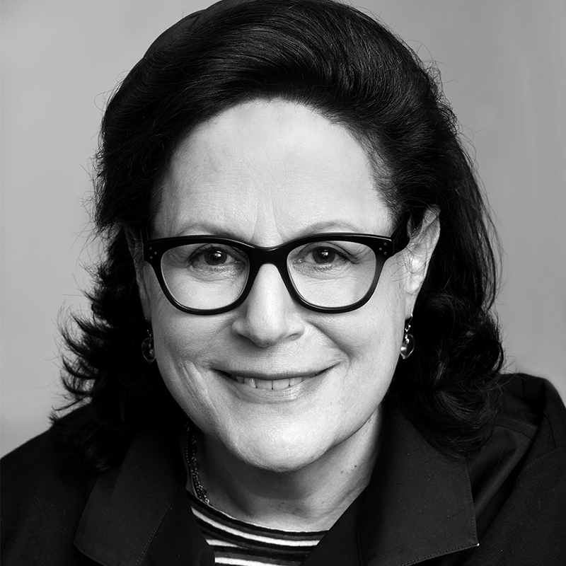 Black and white portrait of a smiling woman with glasses.