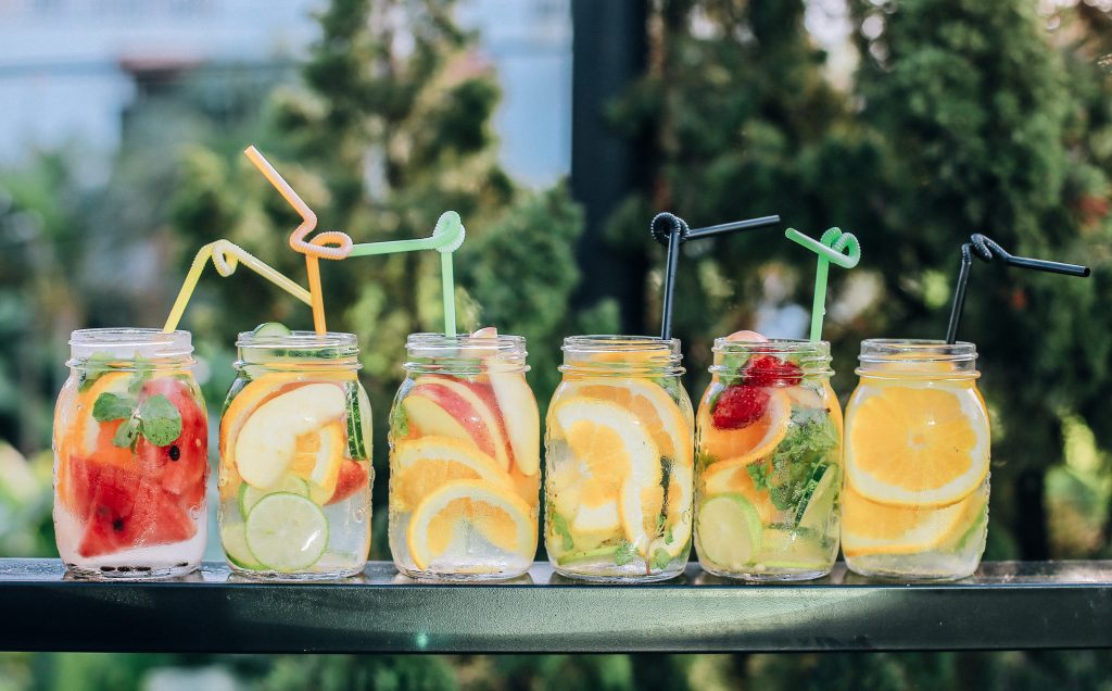 A refreshing lineup of fruit-infused water in mason jars, beautifully garnished and ready to quench your thirst on a sunny day.