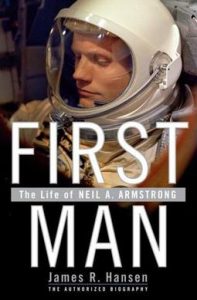 Astronaut in a space helmet with the title "first man" displayed overlaying the image.