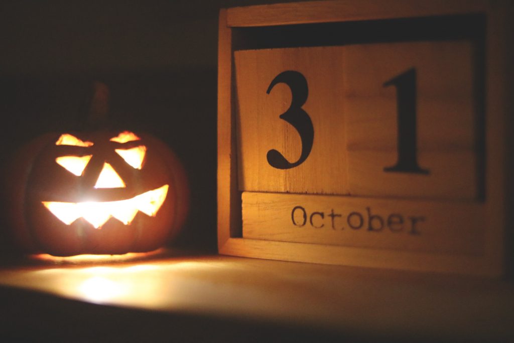 A glowing jack-o'-lantern beside a wooden calendar block displaying october 31, creating a spooky halloween ambiance.