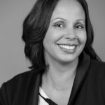Professional woman with a confident smile posing for a black and white headshot.