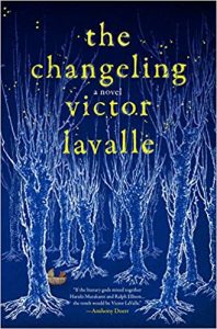 Cover of a novel titled "the changeling" by victor lavalle, featuring an illustration of white tree branches on a blue background with glowing yellow specks and text.