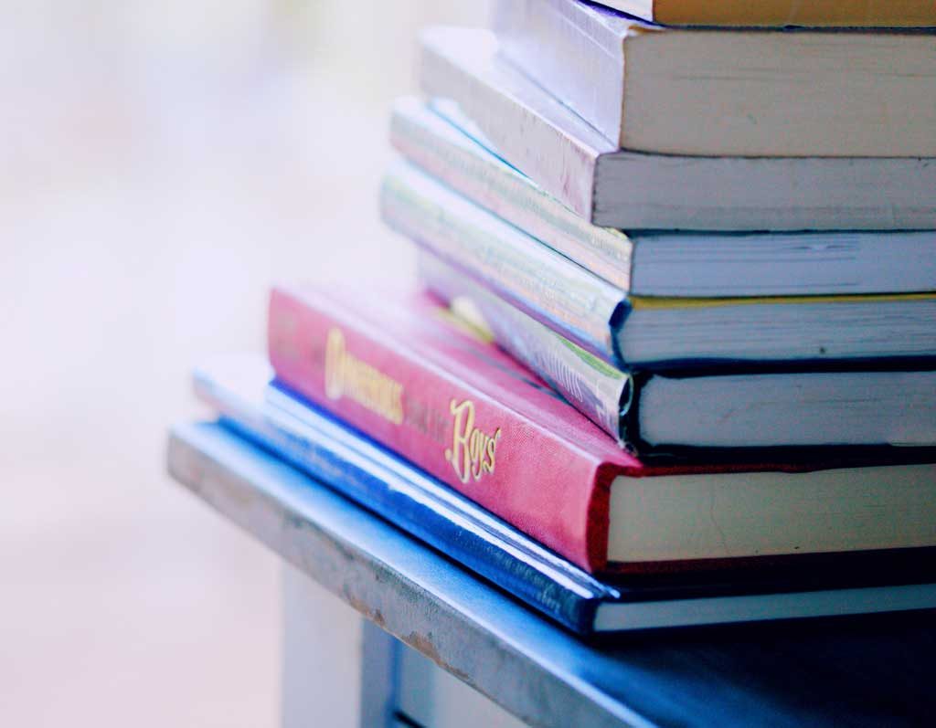 A stack of hardcover books with a blurred background, the tranquility of a reader's haven.