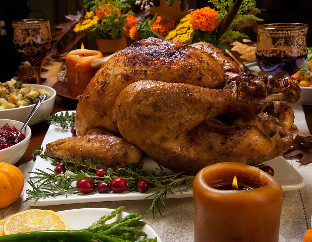 A golden roasted turkey takes center stage on a festive holiday table, surrounded by a variety of side dishes, seasonal decorations, and warm candlelight.