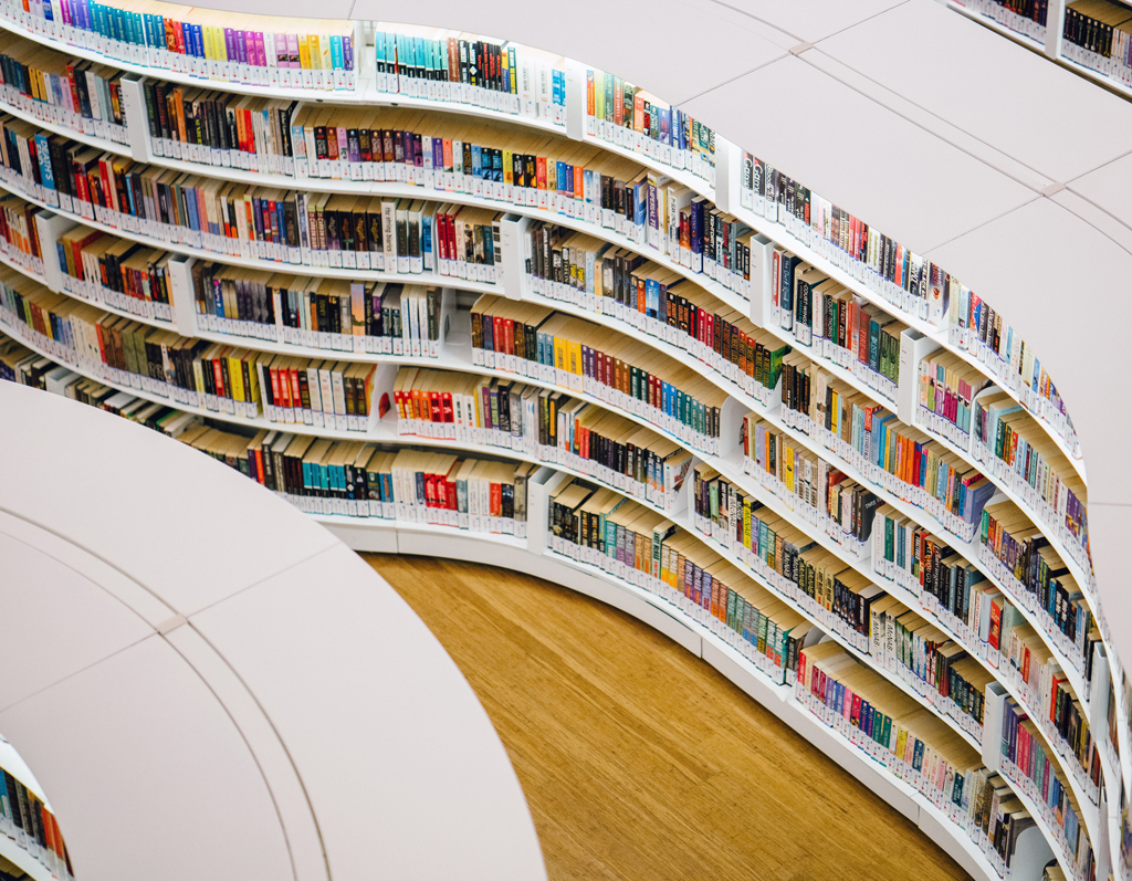 Curved bookshelves forming an elegant cascade of literature in a modern library setting.