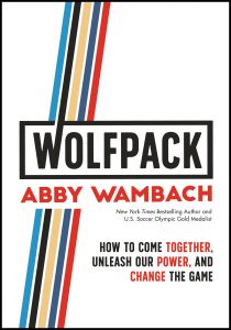 The image is a graphic cover of a book titled "wolfpack" by abby wambach. the cover includes a description of the author as a new york times bestselling author and u.s. soccer olympic gold medalist. below the title is the book's subtitle: "how to come together, unleash our power, and change the game". the design features bold, capitalized text with striking geometric lines in red, blue, and light blue colors on the left side, crossing behind the title text.