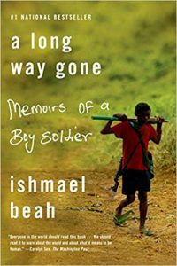 A young boy in a tattered red shirt and shorts, carrying a large military-style rifle over his shoulder, walks along a barren landscape, hinting at the stark realities explored in the memoir "a long way gone" by ishmael beah.