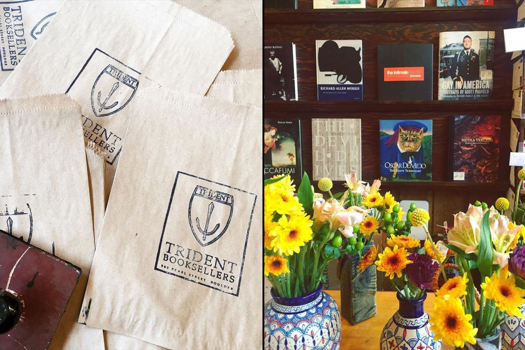 On the left, a collection of brown paper shopping bags with "trident booksellers" printed on them, suggesting a bookstore or literary theme. on the right, a cozy bookstore setting with shelves of books, assorted decorations, and a vibrant display of fresh flowers in patterned vases, creating a warm and inviting atmosphere.