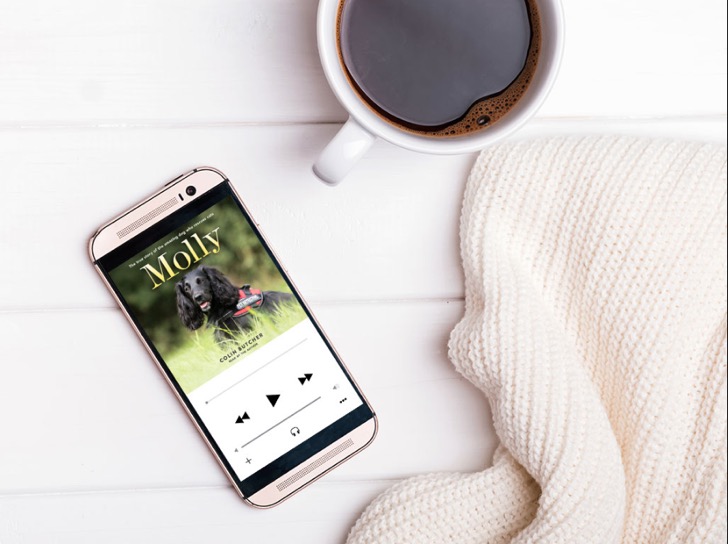 A cozy moment featuring a smartphone displaying a pet profile named "molly" placed on a white surface next to a warm cup of coffee and a comforting knitted blanket.