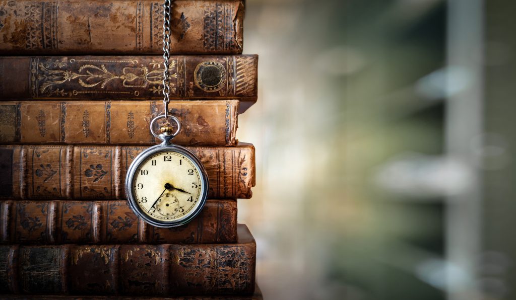 A vintage pocket watch dangles in front of a stack of antique leather-bound books, evoking a sense of timeless wisdom and the enduring journey through history and knowledge.