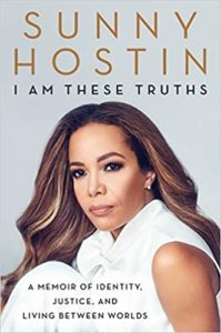 A confident woman with her hair styled in soft waves looks directly at the camera, dressed in a crisp white outfit. the book cover features the title "i am these truths", signaling a personal memoir by the author sunny hostin, focusing on themes of identity, justice, and living between worlds.
