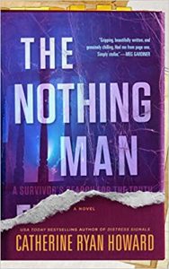 A photograph of a novel titled "the nothing man" by catherine ryan howard, displayed with the book cover facing forward. the cover features striking typography overlaid on an abstract blurred background in shades of purple and blue, with a torn white edge design along the bottom.