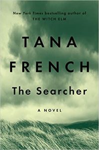 The cover of tana french's novel 'the searcher', featuring a moody landscape with rolling, grass-covered hills under a stormy sky, invoking a sense of mystery and foreboding.