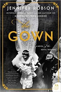 The image is of a book cover featuring the title "the gown" by jennifer robson, highlighted as a novel of the royal wedding. the cover design includes a vintage photograph of two women in elegant attire, with the one in front showcasing a long, flowing gown, indicating a historical or regal theme associated with the book's content.