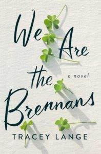 A tranquil book cover for "we are the brennans" by tracey lange, featuring a minimalist design with sprigs of green clover laid out against a textured off-white background.