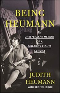 The image is the cover of a book entitled "being heumann: an unrepentant memoir of a disability rights activist" by judith heumann with kristen joiner. the cover features a black and white photograph of judith heumann, a renowned disability rights activist, seated in a wheelchair. she appears to be in conversation or deep thought, captured in a moment that suggests determination and contemplation.