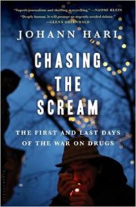 Book cover of 'chasing the scream: the first and last days of the war on drugs' by johann hari, featuring a silhouette of a person against a backdrop of twinkling lights.