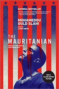 The image is a graphic cover design for the book "guantánamo diary" by mohamedou ould slahi, edited by larry siems. the cover is stylized with red and white vertical stripes resembling the american flag in the background, and a blue silhouette of a man's head in the foreground, invoking themes of justice, captivity, and the united states judicial system. there is text overlay in white and yellow indicating the book's critical acclaim and that it has been adapted into a major motion picture titled "the mauritanian.