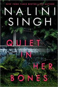 A book cover for "quiet in her bones" by new york times bestselling author nalini singh, featuring a moody and mysterious backdrop of a forest partially obscuring a vehicle, hinting at a suspenseful or thriller genre story.