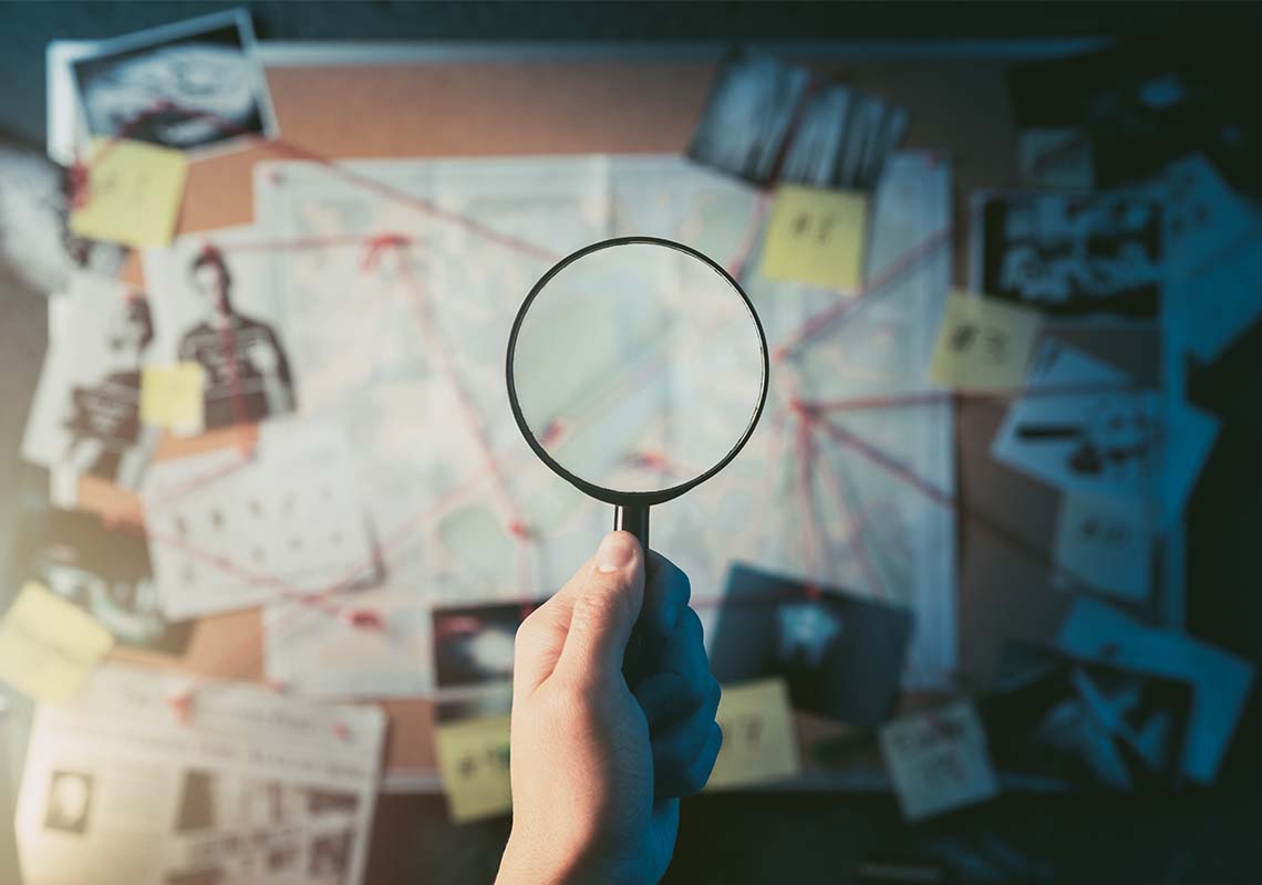 A detective piecing together clues: hand holding a magnifying glass over a board of evidence with photos and connections.