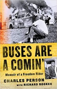 A powerful book cover showcasing a historical moment with a burning bus in the background and a person crouched in the foreground, titled "buses are a comin'" - memoir of a freedom rider by charles person with richard rooker.