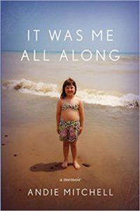 A young girl stands on a sandy beach with the ocean behind her, under a serene sky, featured on the cover of andie mitchell's memoir titled "it was me all along.