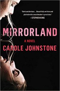 The image shows the cover of a novel titled "mirrorland" by carole johnstone. the cover art features an upside-down close-up of a woman's face, with strands of her hair falling upwards, set against a black background, which creates a mirror image effect complementing the book's title. the text on the cover includes a praising quote from stephen king, describing the book as "dark and devious... beautifully written and plotted with a watchmaker's precision.