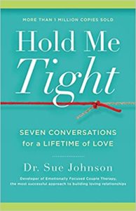 The image shows the cover of a book titled "hold me tight: seven conversations for a lifetime of love" by dr. sue johnson. the cover has a light green background with the title in large yellow and white letters. there is a red string or thread that appears to be tying a knot, symbolizing connection and bonding, which relates to the book's focus on fostering successful romantic relationships through emotional bonding.