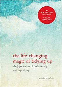A minimalist book cover with serene watercolor background, featuring "the life-changing magic of tidying up: the japanese art of decluttering and organizing" by marie kondo, marked as a new york times best seller with over 3 million copies sold.