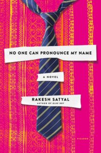 A book cover featuring a sophisticated navy blue tie with diagonal stripes against a vibrant pink and orange fabric backdrop, alongside the title "no one can pronounce my name" by rakesh satyal, suggesting a narrative woven with themes of identity and cultural contrast.