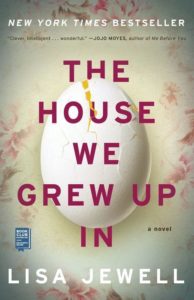 A book cover featuring a large cracked egg against a floral background, titled "the house we grew up in" by lisa jewell, with a quote from jojo moyes praising the novel at the top.