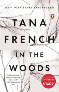 Cover of the book "in the woods" by tana french, a new york times bestseller and the inspiration for the dublin murders starz series, featuring a backdrop of stark tree branches.