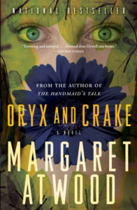 An artistic book cover featuring a large blue flower with a human eye at the center, overlaid on a yellow-green textured background suggestive of leaves or foliage, for margaret atwood's novel "oryx and crake," with the tagline "national bestseller" and praise comparing it favorably to george orwell's work.