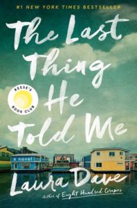 A colorful book cover for the novel "the last thing he told me" by laura dave, featuring houseboats on calm waters under a cloudy sky, with the accolade of being a #1 new york times bestseller and a part of reese's book club.