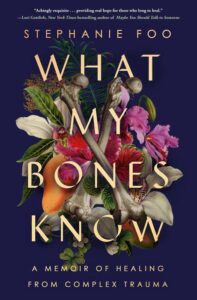 A book cover titled "what my bones know" by stephanie foo, depicting a visually compelling arrangement of natural elements such as flowers, bones, and fruit, symbolizing themes of healing and growth from complex trauma.