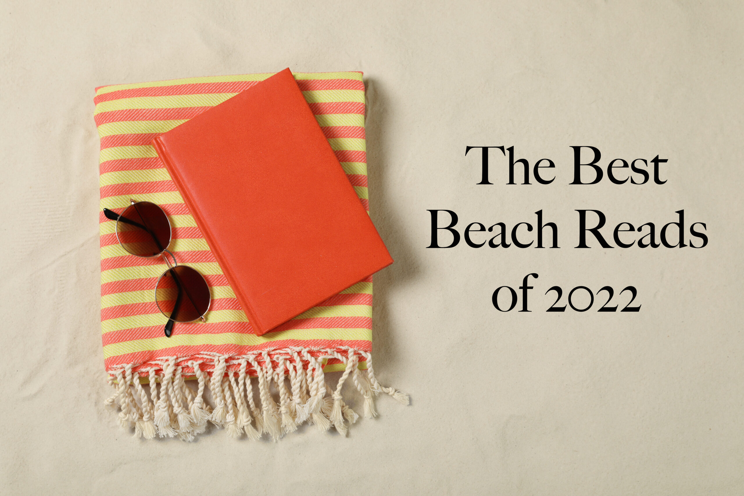 A bright orange book atop a striped beach towel with a pair of sunglasses, suggesting a perfect setup for a summer read.