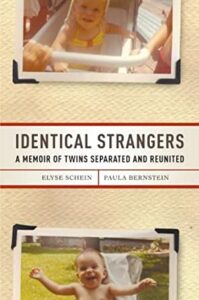 A book cover titled "identical strangers - a memoir of twins separated and reunited" by elyse schein and paula bernstein, featuring two photographs of what appears to be the same baby smiling, displayed in an overlaid style against a textured background.