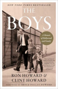 A black and white photo featured on a book cover titled "the boys: a memoir of hollywood and family" by ron howard and clint howard, with a foreword by bryce dallas howard, showing two young brothers hand in hand being led by their father, likely capturing a moment from their early life in show business.