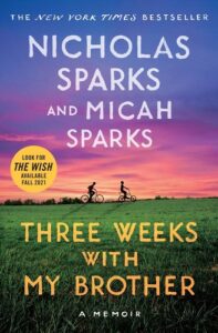 A book cover for "three weeks with my brother" by nicholas sparks and micah sparks, featuring a sunset sky and two figures riding bicycles across a green field.