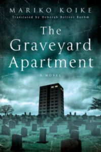 A chilling book cover featuring a lone, dark apartment building towering over a gloomy graveyard under a stormy sky, titled "the graveyard apartment" by mariko koike, translated by deborah boliver boehm.