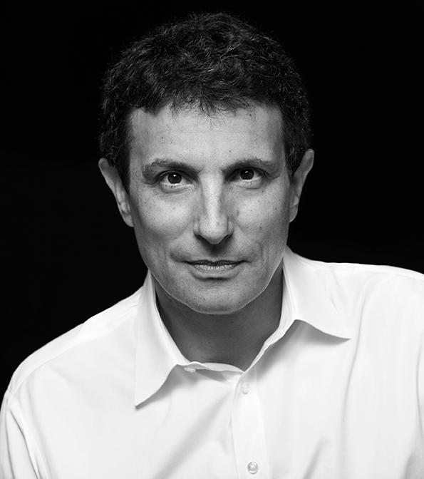 Black and white portrait of a thoughtful man in a white shirt against a dark background.