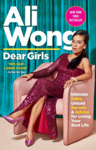 A woman in a chic, sequined burgundy dress sits confidently on a pink armchair, her pose and expression exuding elegance and strength, while the cover boasts engaging content from intimate tales to advice for living your best life.