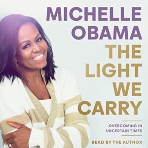A smiling woman on a book cover titled "the light we carry: overcoming in uncertain times" read by the author.