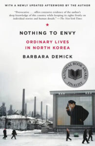 Cover of 'nothing to envy: ordinary lives in north korea' by barbara demick featuring a wintry scene with a solitary figure peering through binoculars against a backdrop of a gray cityscape.