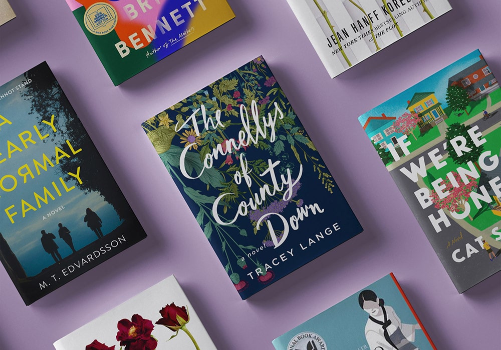 A collection of colorful books spread out over a purple surface, showcasing a variety of titles and authors with diverse cover designs.
