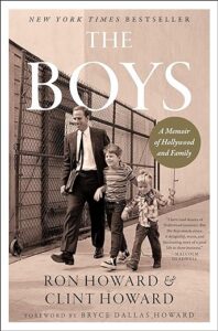 A sepia-toned cover of "the boys: a memoir of hollywood and family" by ron howard and clint howard, depicting two young boys walking hand in hand with a distinguished-looking man, evoking a sense of nostalgia and family ties within the entertainment industry.