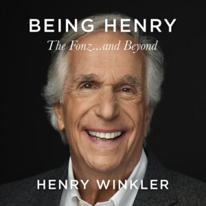 A portrait of an elderly man with a warm smile, grey hair, and smart attire on a black background with the text "being henry the fonz...and beyond" at the top and the name "henry winkler" at the bottom, representing a personal brand or the cover of a biography.