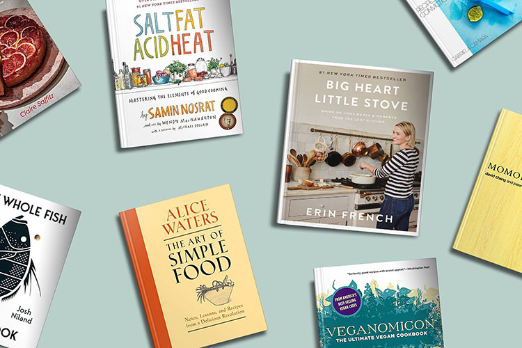 An assortment of culinary books laid out, including titles focused on fundamental cooking principles, whole ingredient usage, and vegetarian recipes, suggesting a theme of diverse culinary literature.