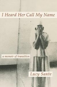 A person stands against a light background, their face obscured by their hands as if in distress or contemplation, on a book cover titled "i heard her call my name: a memoir of transition" by lucy sante.